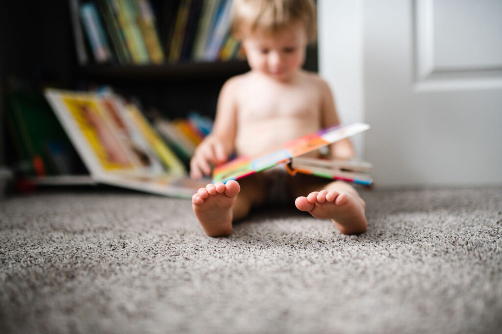 toddler reading on floor with book in lap